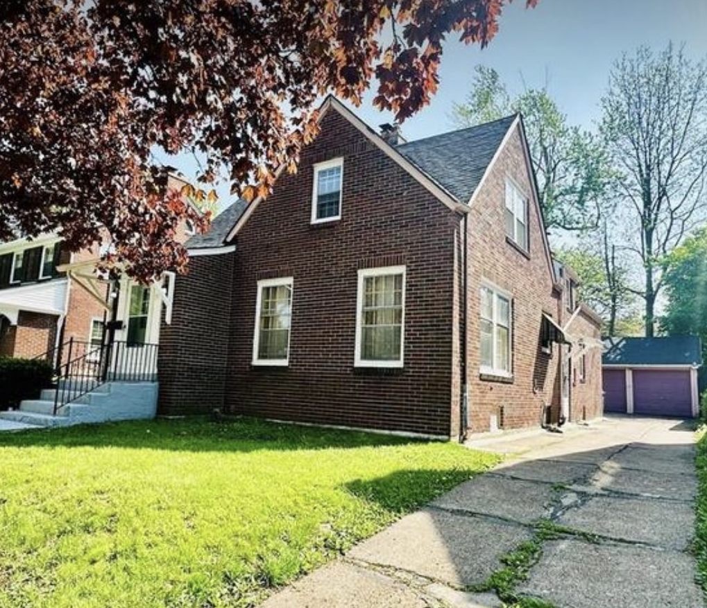 Brick home with a private driveway and detached garage on a tree-lined Buffalo street
